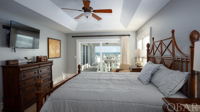 bedroom with access to exterior, a raised ceiling, ceiling fan, and baseboards