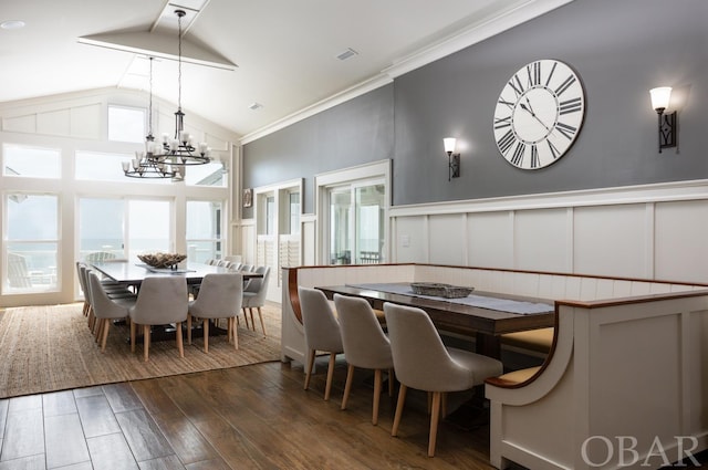 dining space with high vaulted ceiling, a notable chandelier, a decorative wall, visible vents, and dark wood finished floors