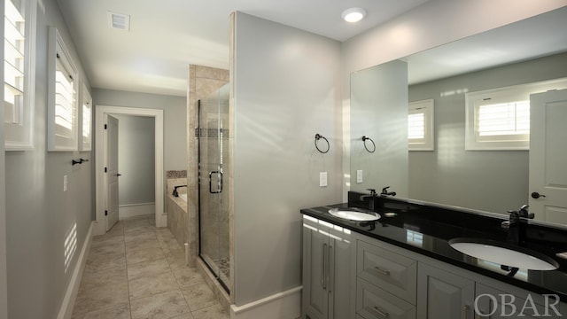 bathroom with double vanity, a sink, a shower stall, and a bath