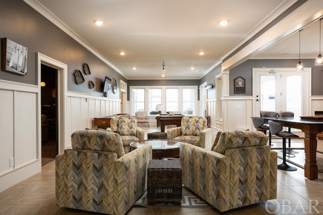 living area featuring wainscoting, ornamental molding, ornate columns, a decorative wall, and recessed lighting