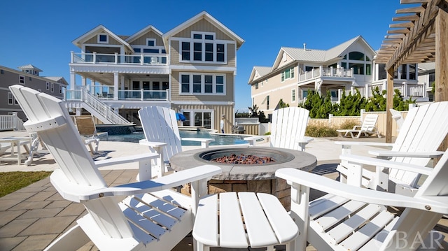 rear view of house featuring a fire pit, a fenced in pool, a residential view, a patio area, and board and batten siding