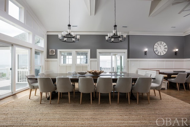 dining space featuring a towering ceiling, a chandelier, and wainscoting