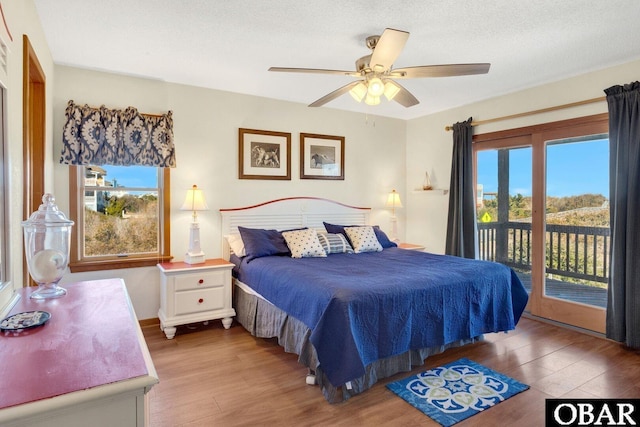 bedroom with ceiling fan, multiple windows, wood finished floors, and access to exterior