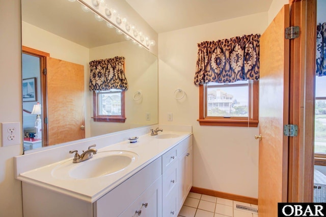 full bathroom with double vanity, baseboards, visible vents, and a sink