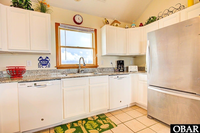 kitchen with white dishwasher, white cabinets, a sink, and freestanding refrigerator