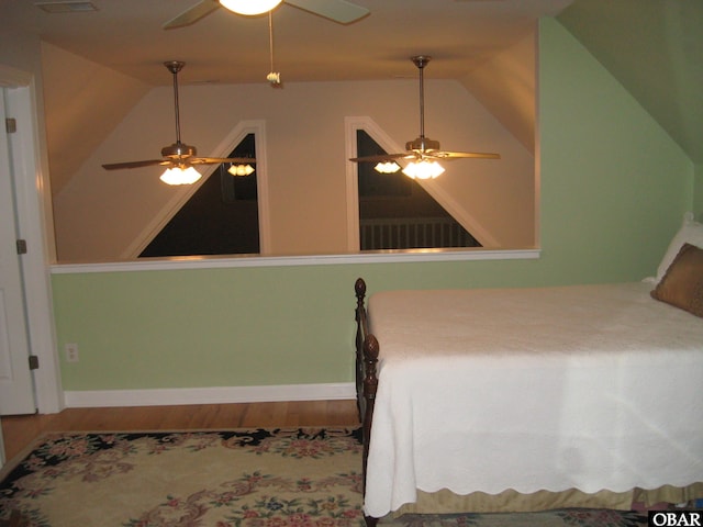 bedroom featuring a ceiling fan, vaulted ceiling, baseboards, and wood finished floors