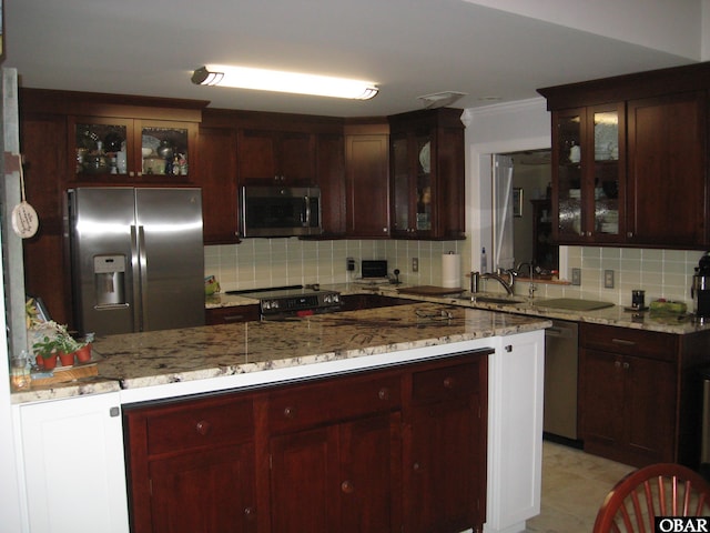 kitchen with appliances with stainless steel finishes, glass insert cabinets, light stone counters, and decorative backsplash