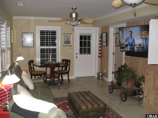 living area featuring baseboards, visible vents, a ceiling fan, and crown molding