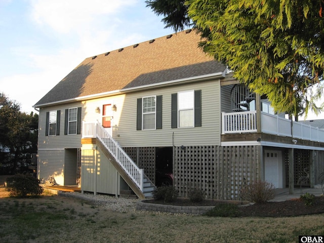 back of property with a shingled roof, stairway, and a garage