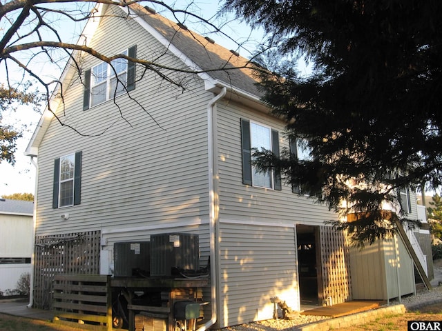 view of home's exterior featuring cooling unit and roof with shingles