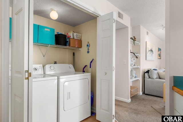 washroom featuring laundry area, visible vents, light colored carpet, washer and clothes dryer, and a textured ceiling
