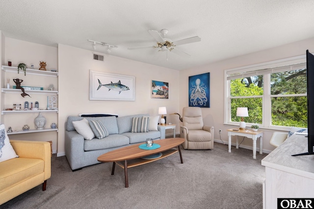 living area featuring visible vents, a textured ceiling, carpet floors, and ceiling fan