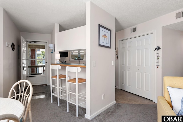 interior space featuring carpet flooring, a textured ceiling, visible vents, and baseboards