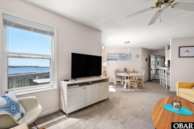 carpeted living room featuring a textured ceiling, ceiling fan, and baseboards