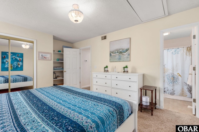 bedroom featuring connected bathroom, carpet floors, a textured ceiling, baseboards, and visible vents