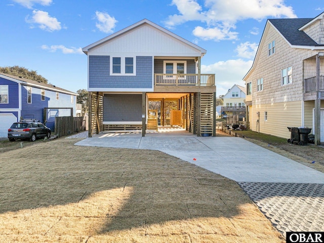 beach home featuring concrete driveway, covered porch, and stairway