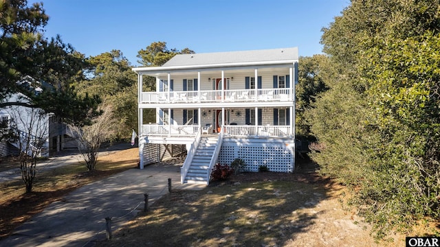 view of front of property with a carport, covered porch, driveway, and stairs