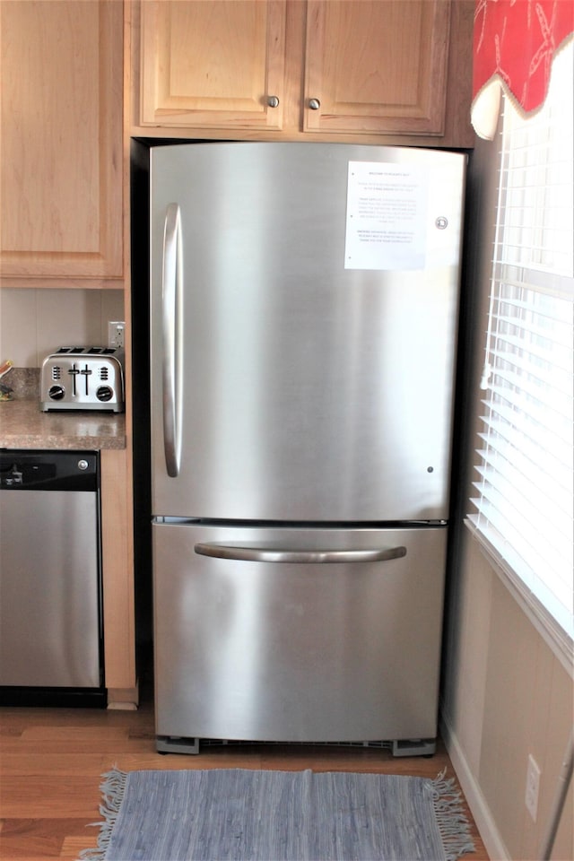 kitchen with appliances with stainless steel finishes, light brown cabinets, and dark wood-style floors