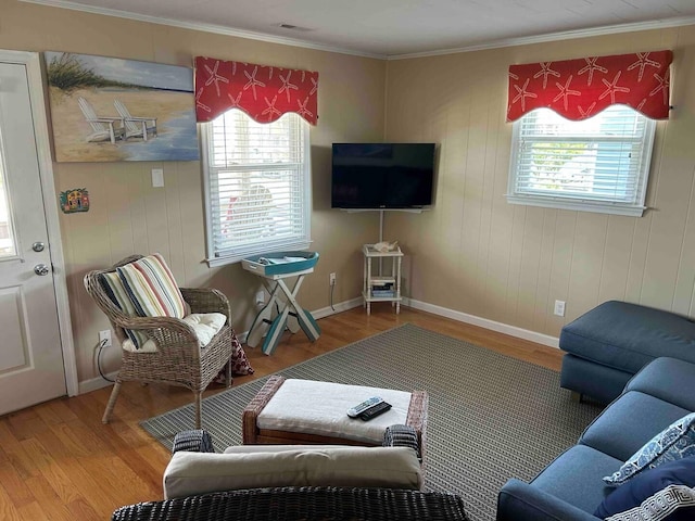 living area with baseboards, ornamental molding, and wood finished floors