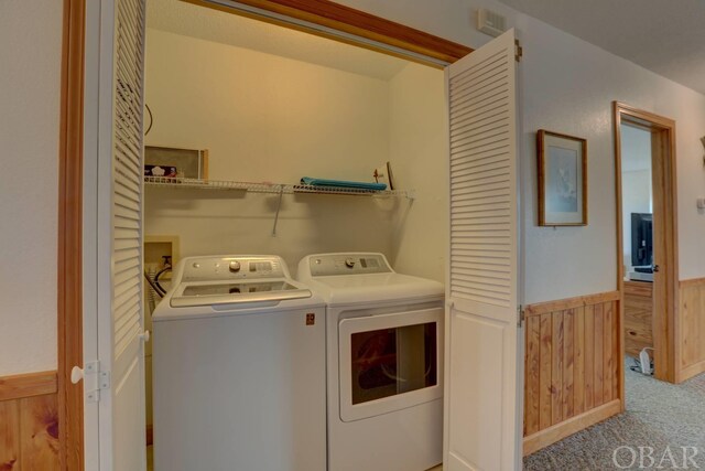 laundry area with light carpet, laundry area, wooden walls, washer and clothes dryer, and wainscoting