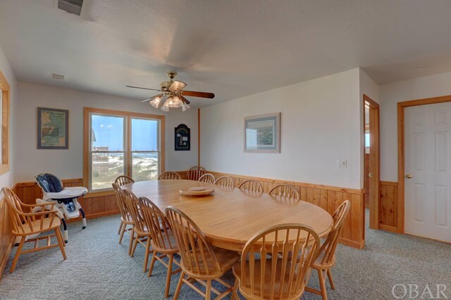 dining space with visible vents, a wainscoted wall, wood walls, and light carpet