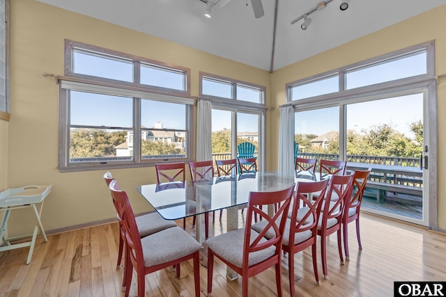 dining space featuring rail lighting, light wood-style flooring, vaulted ceiling, and a ceiling fan