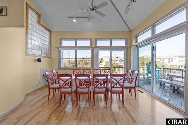 dining space with light wood-type flooring, plenty of natural light, and lofted ceiling