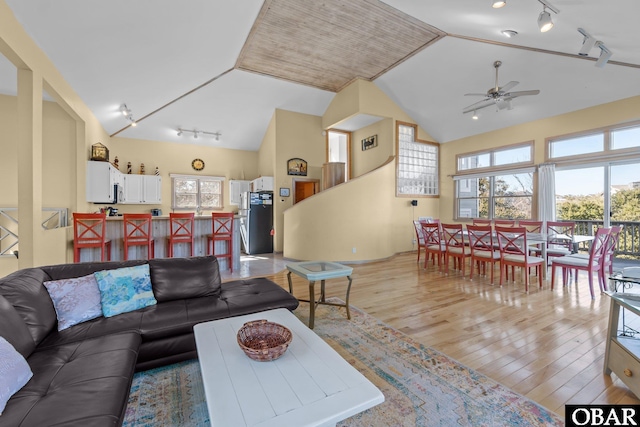 living area with light wood-style floors, a wealth of natural light, and vaulted ceiling