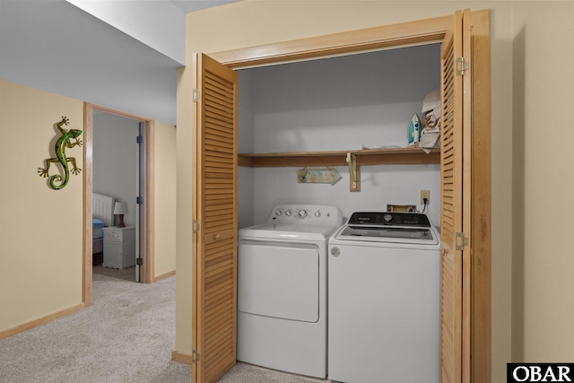 clothes washing area with light carpet, laundry area, baseboards, and washer and dryer