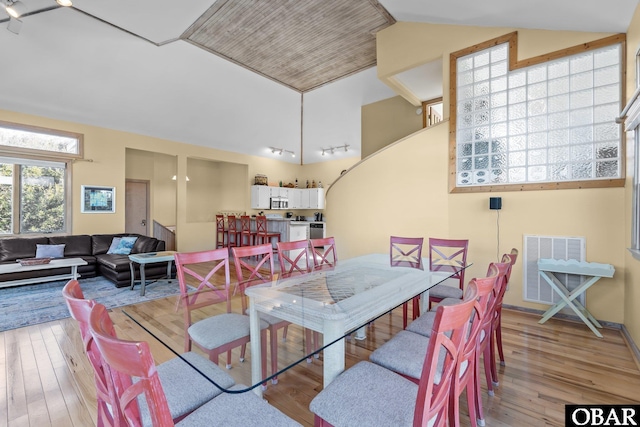 dining space featuring vaulted ceiling, wood-type flooring, and visible vents