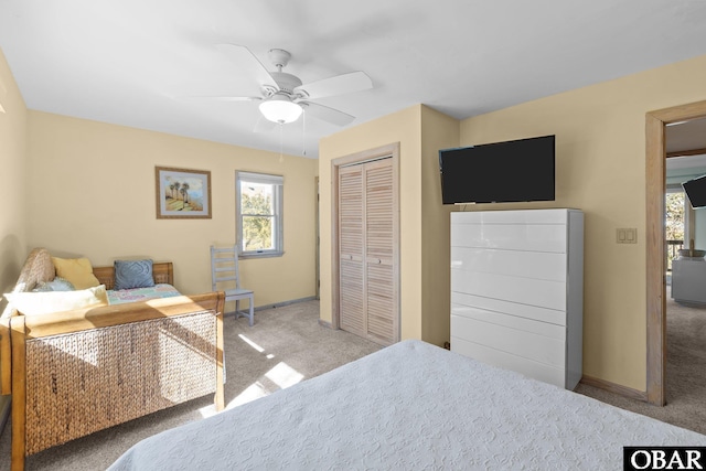 carpeted bedroom featuring a ceiling fan, a closet, and baseboards