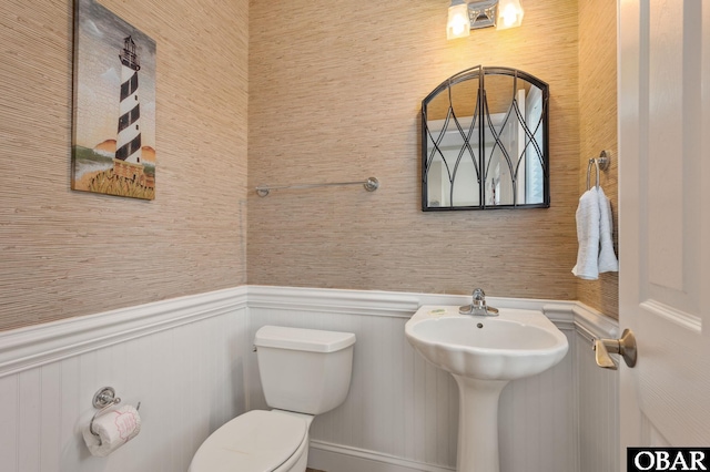 half bathroom with a wainscoted wall and toilet