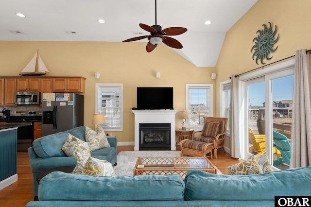 living area with recessed lighting, lofted ceiling, wood finished floors, ceiling fan, and a fireplace