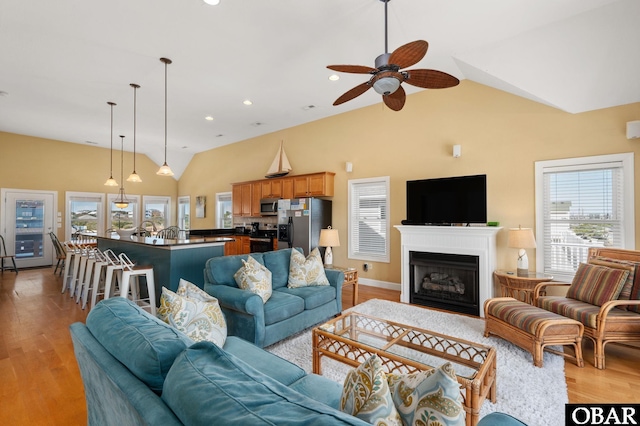 living area with light wood-type flooring, ceiling fan, a fireplace, lofted ceiling, and recessed lighting