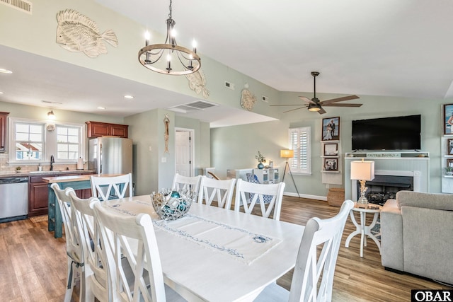 100 Amherst Dr Unit 3, Kill Devil Hills, NC 27948 - dining room featuring lofted ceiling, wood finished floors, a fireplace, a chandelier, and ceiling fan