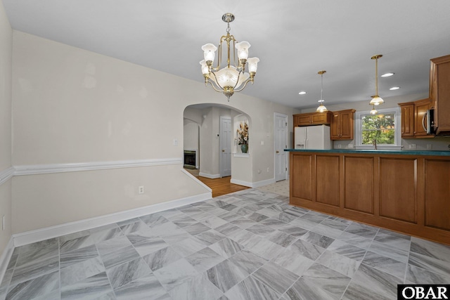 604 W First St Lot 321, Kill Devil Hills, NC 27948 - kitchen featuring white refrigerator with ice dispenser, arched walkways, brown cabinetry, hanging light fixtures, and baseboards