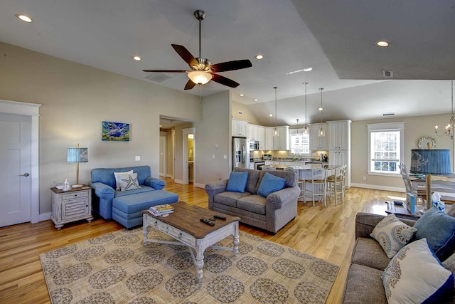 living room featuring ceiling fan with notable chandelier, light wood-type flooring, baseboards, and recessed lighting