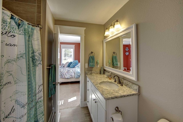 bathroom with a textured wall, ensuite bathroom, vanity, wood finished floors, and a shower with curtain