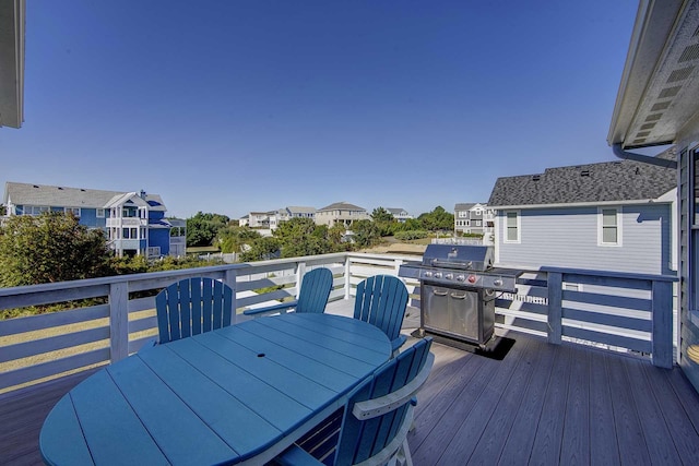 deck with outdoor dining space, grilling area, and a residential view