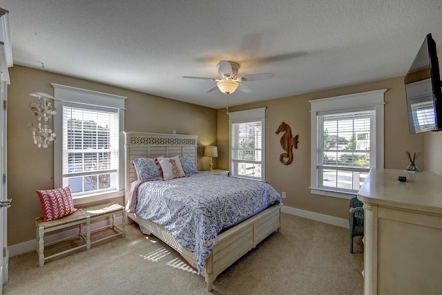 bedroom with light carpet, ceiling fan, a textured ceiling, and baseboards