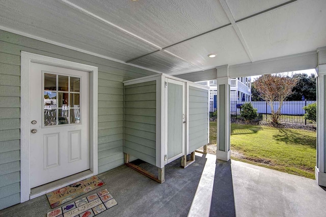 view of exterior entry featuring a lawn and fence