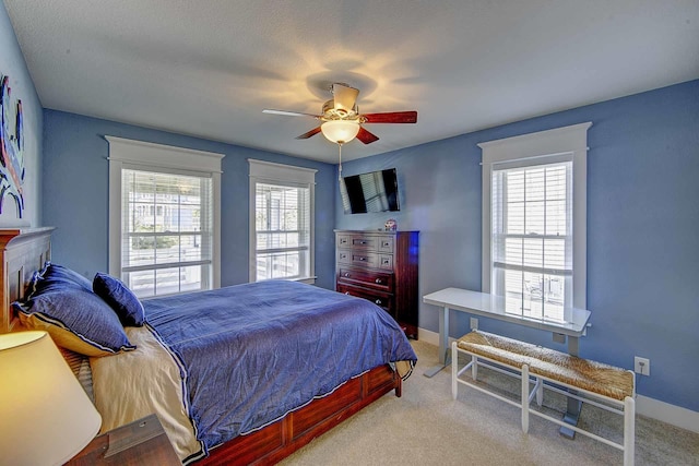 carpeted bedroom with multiple windows, ceiling fan, and baseboards