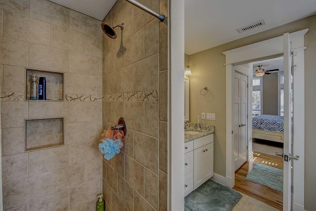 bathroom with vanity, visible vents, a ceiling fan, tiled shower, and ensuite bath