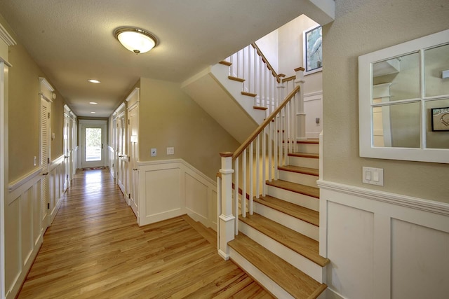 interior space with recessed lighting, a decorative wall, wood finished floors, and wainscoting