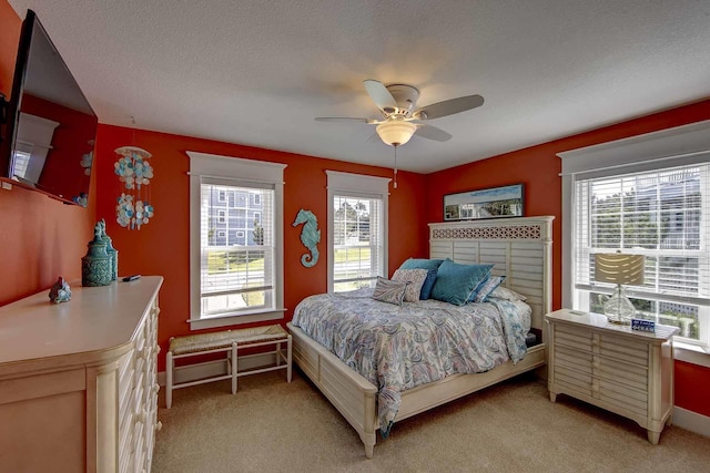 bedroom featuring ceiling fan, a textured ceiling, and light colored carpet