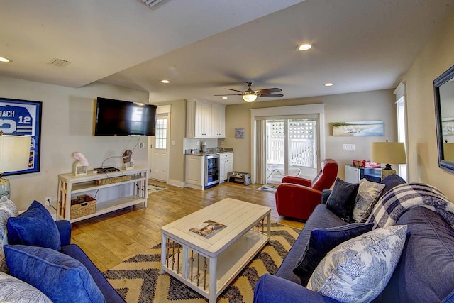 living room with light wood-style floors, a wealth of natural light, beverage cooler, and recessed lighting