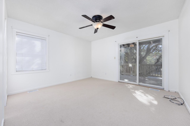 unfurnished room with light colored carpet, ceiling fan, visible vents, and baseboards