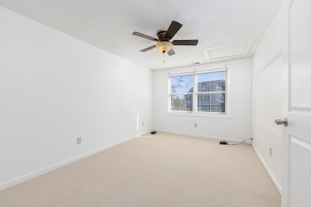 carpeted spare room featuring attic access, ceiling fan, a textured ceiling, and baseboards