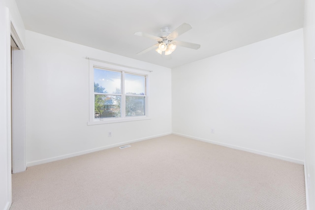 unfurnished room featuring light carpet, baseboards, and a ceiling fan