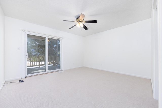 spare room featuring light colored carpet, ceiling fan, and baseboards